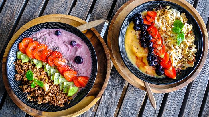 Looking down on two smoothie bowls full of colorful fruit and grains
