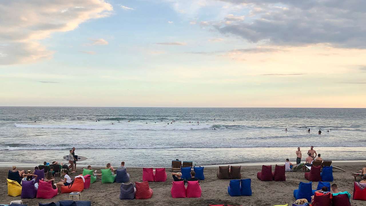 People sitting on bean bags on the beach watching the sun set