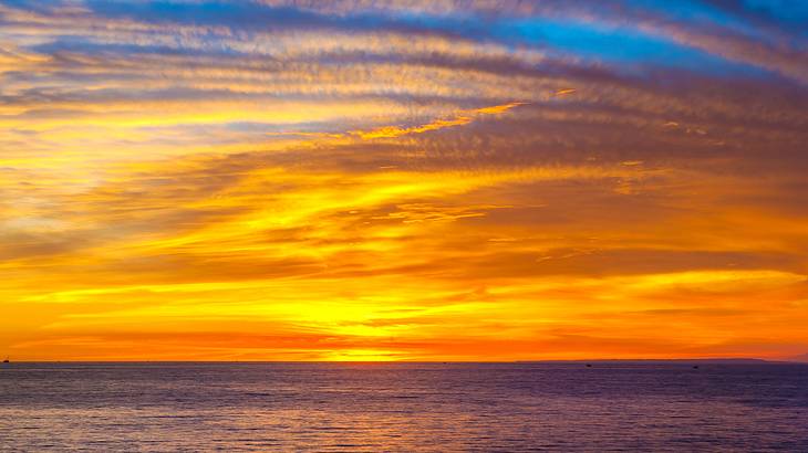 The sun setting over water with the sky bathed in golden colors