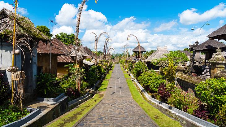 A cobbled street lined with small houses against a partly cloudy sky on a sunny day