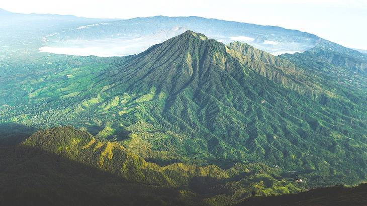 A mountain covered in green vegetation with a crater behind it