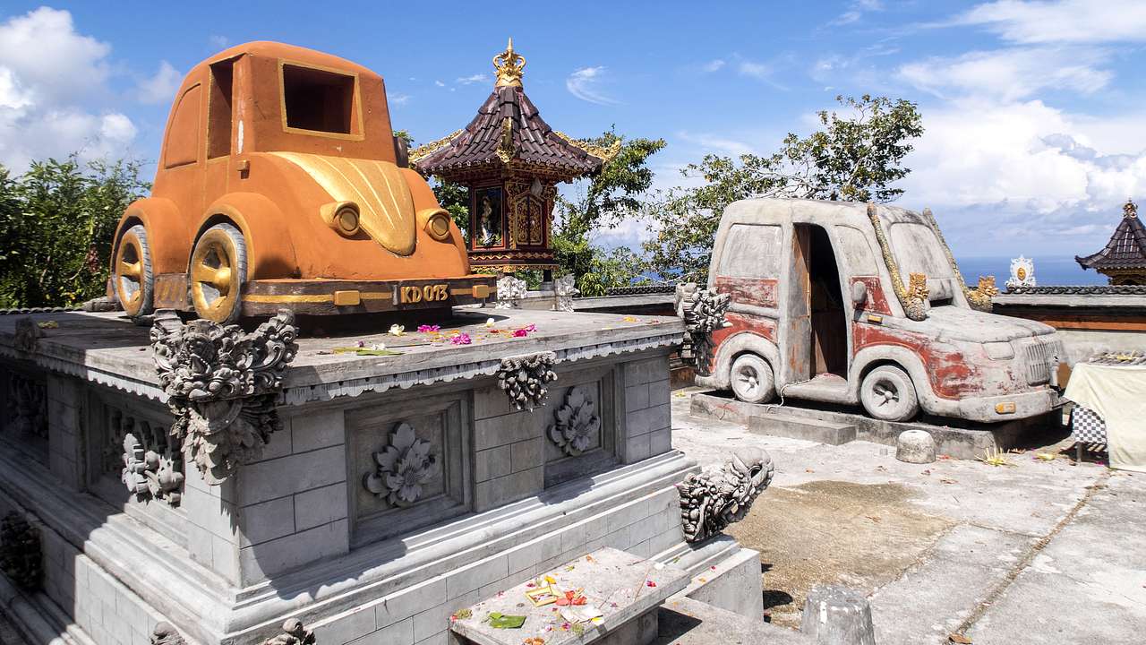A temple shrine alongside an orange car on a cement block
