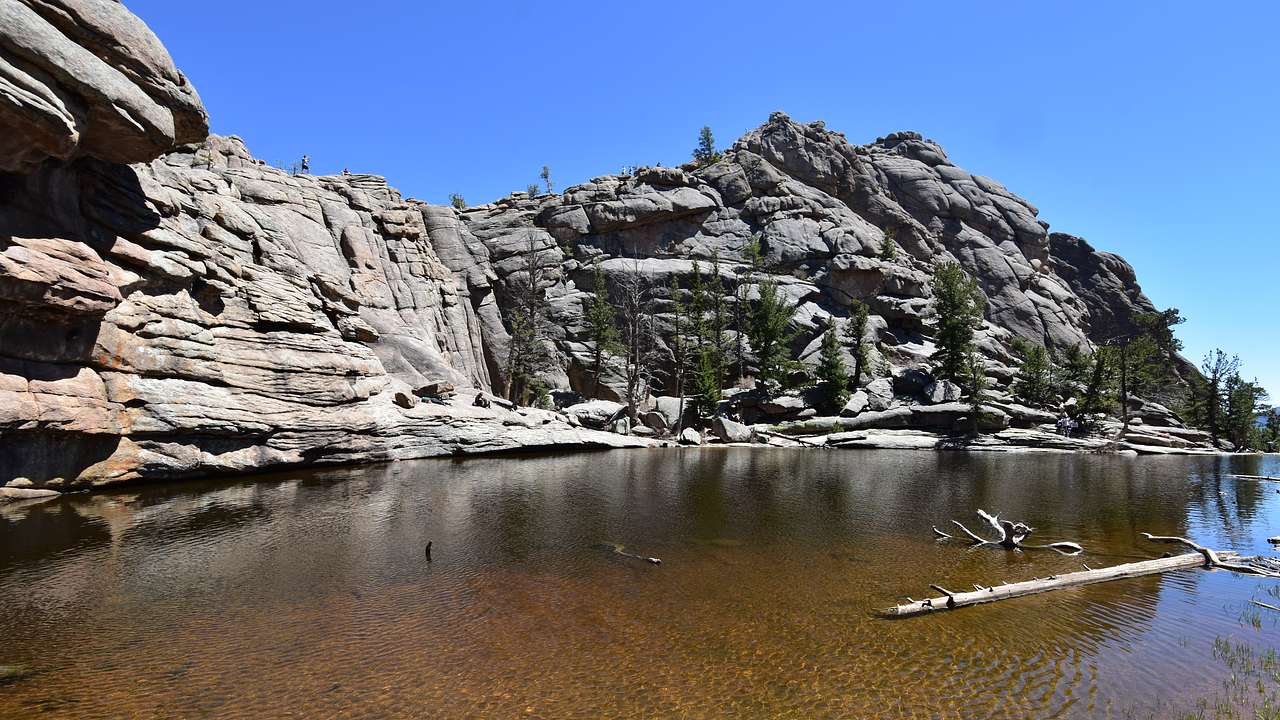 A lake with a rocky mountain in the background