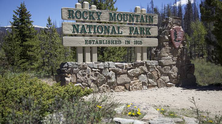 A sign on a rock wall made of wood, "Rocky Mountain National Park"