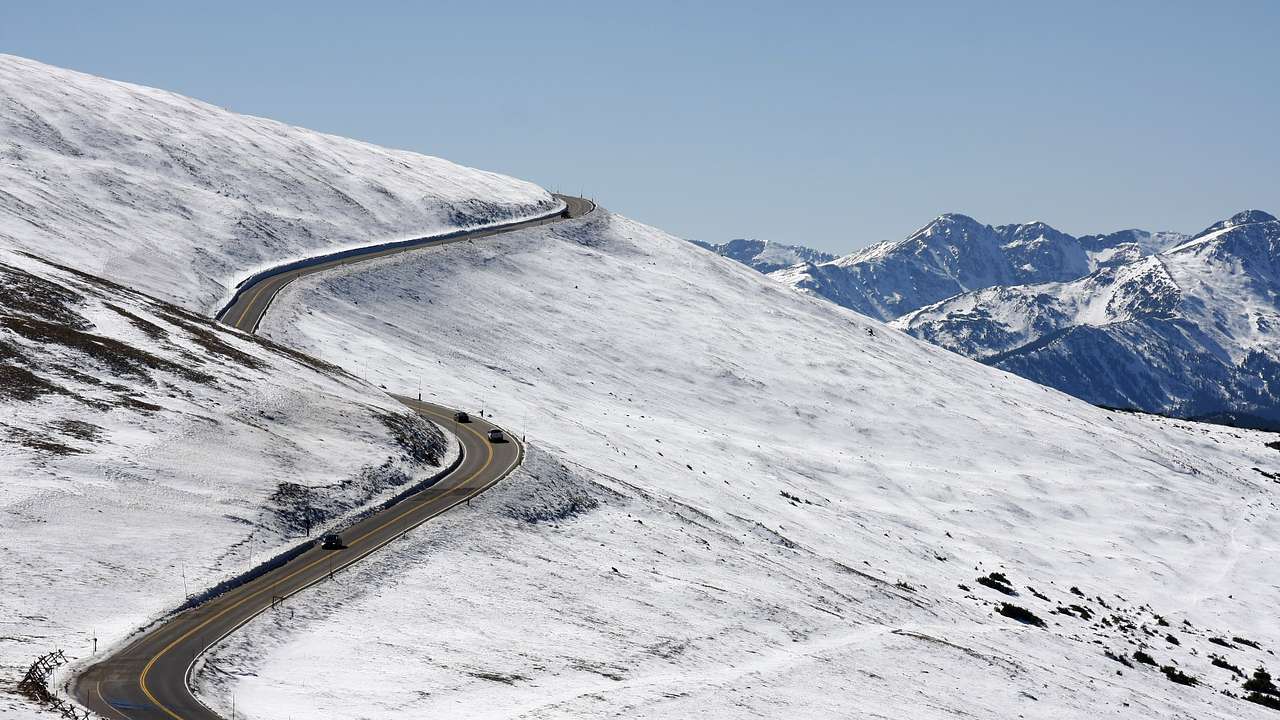 A winding road in the snow with mountains in the distance
