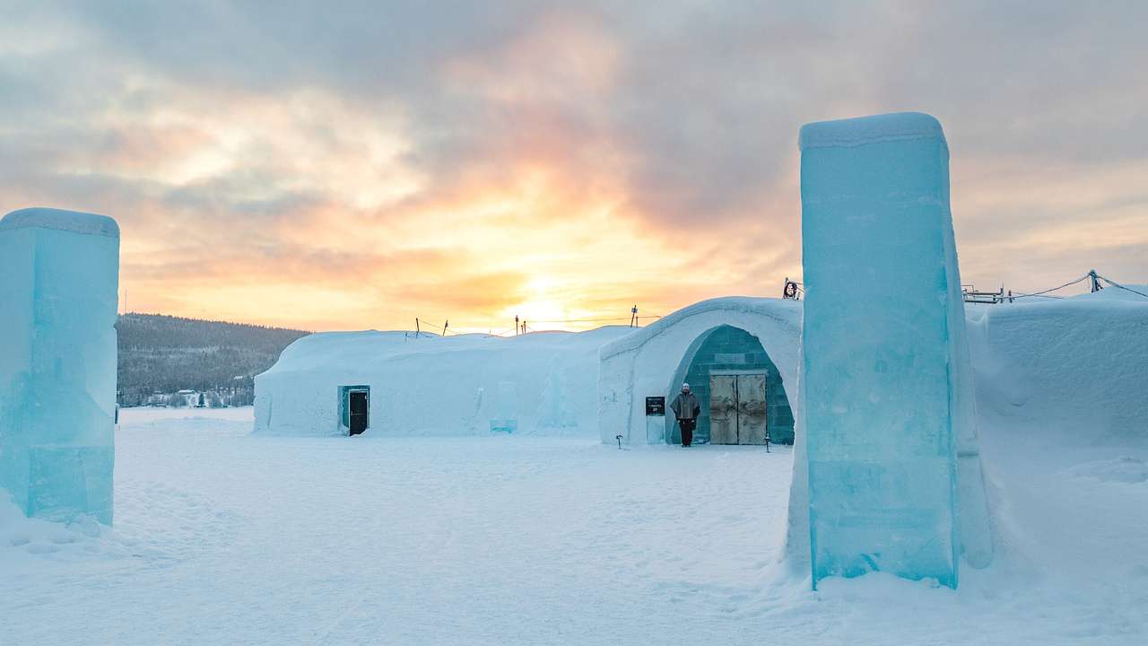 An igloo-like building surrounded by snow at sunset