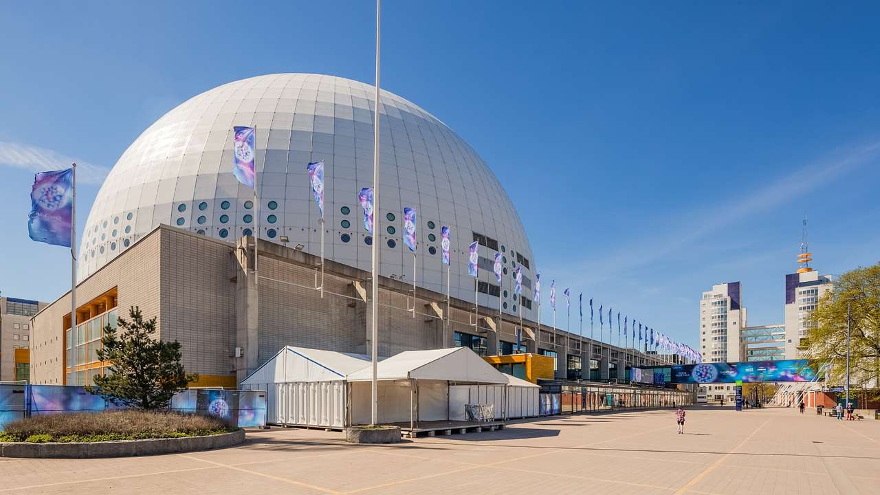 A white sphere-shaped building next to a walkway and flags