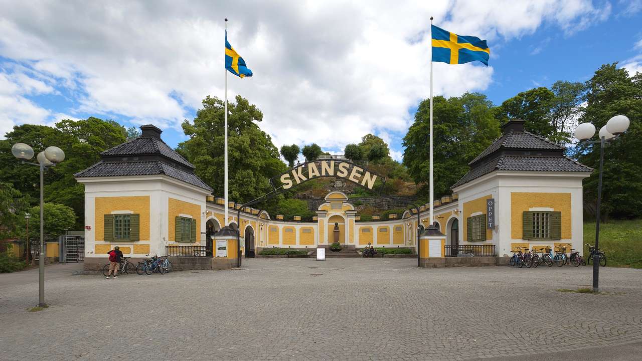 The entryway to an attraction with a "Skansen" sign and Swedish flags