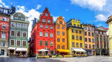 Brightly coloured European buildings in a square under a bright blue sky with clouds