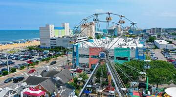 A large Ferris wheel surrounded by cars and buildings