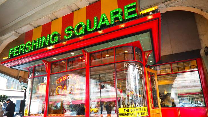 A red cafe with a green sign that says "Pershing Square"