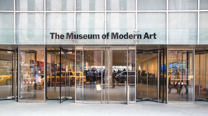 The front of a museum with glass doors and a "Museum of Modern Art" sign