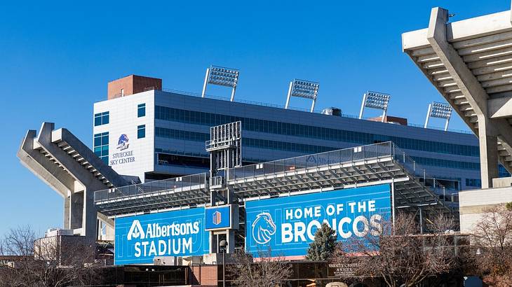 A stadium with blue banners that say " Albertsons Stadium, Home of the Broncos"