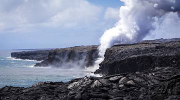 Volcanic cliffs by the ocean with steam coming out of the water