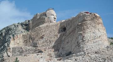 A rock cliff with the face of a man carved into it under a blue sky