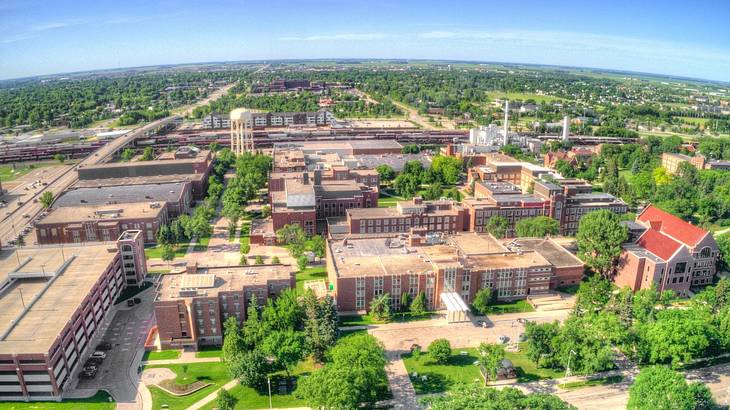 An aerial of buildings surrounded by greenery and trees under a sky An aerial of buildings surrounded by greenery and trees under a sky