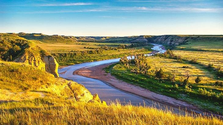 A river winding through a green hilly area A river winding through a green hilly area