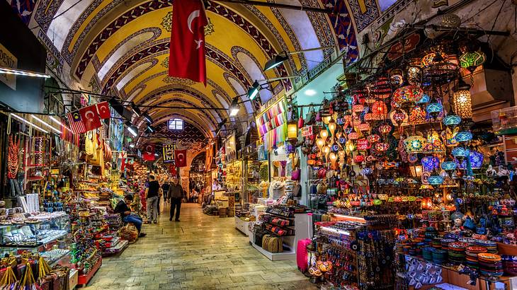 An indoor market with colourful stalls, a mosaic ceiling, and a Turkish flag