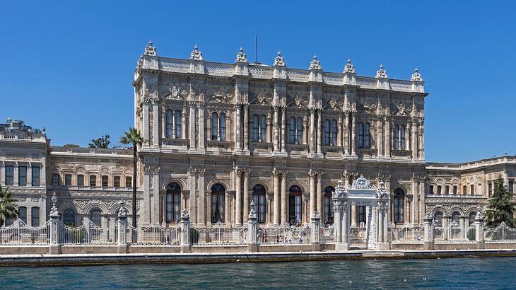 A large palace building with columns next to a body of water and a blue sky
