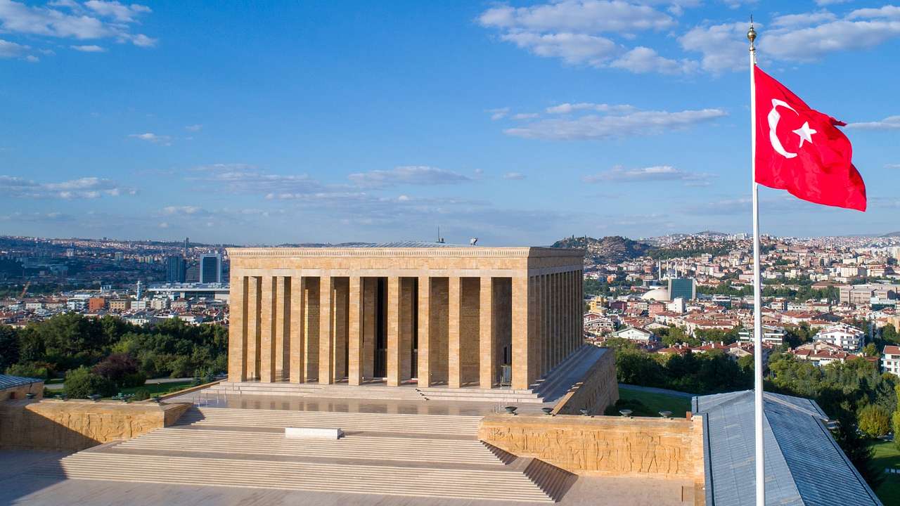 A large stone building with columns and a Turkish flag to the side