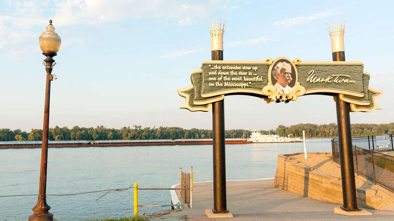 A pathway by a river, with a street light and a sign that reads, "Mark Twain"