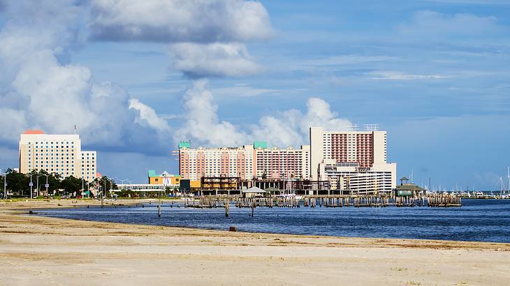 Buildings along the white sand beach and a wooden pier extending into the bay Buildings along the white sand beach and a wooden pier extending into the bay