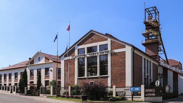 A brick building with flags and bushes next to it on a clear day
