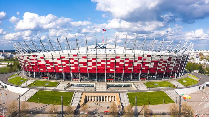 A red and white large stadium with a sign that says "PGE Narodowy"