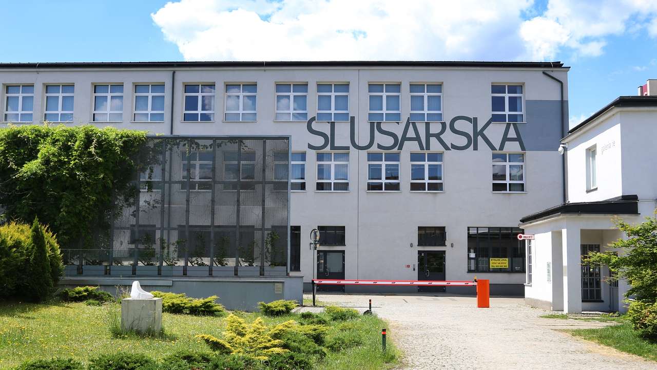A white industrial-style building with a sign on it that says "Slusarska"