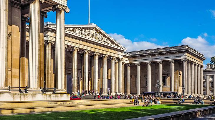 Outside facade of British Museum with tall columns and green grass in front, London