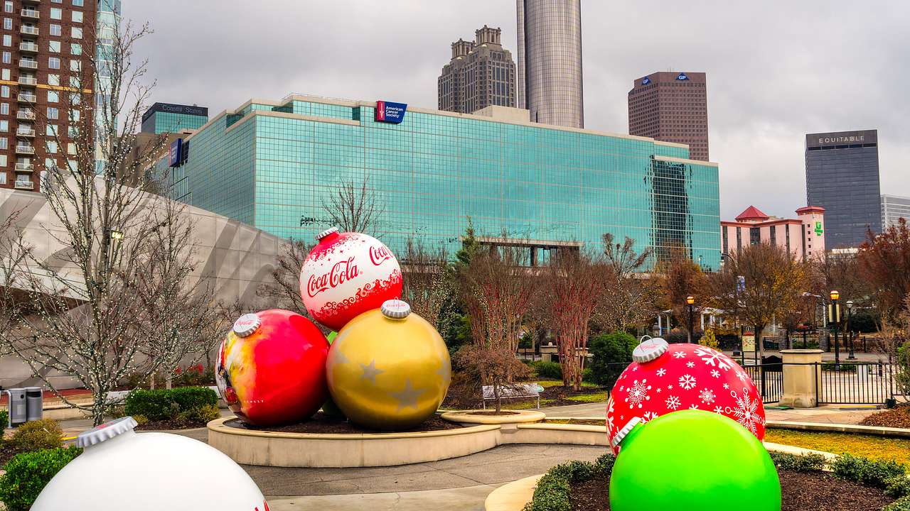 A park with large Christmas ornaments and buildings in the background