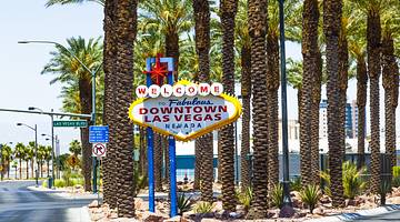 A colorful "Downtown Las Vegas" sign on the street with palm trees behind it