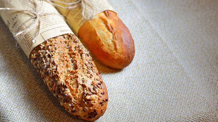 Two crunchy baguettes on a surface covered in plain off-white cloth