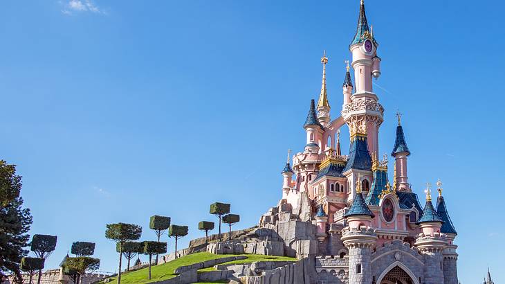 A tall pink and purple castle next to greenery under clear blue skies