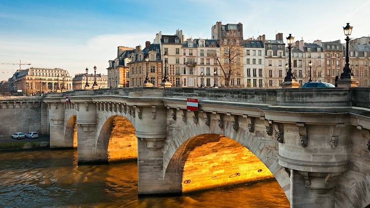 A multi-arched bridge on top of a river with old historic buildings at the back