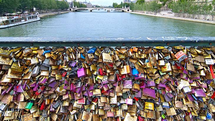 Love locks on a bridge wall, with another bridge over water at the back