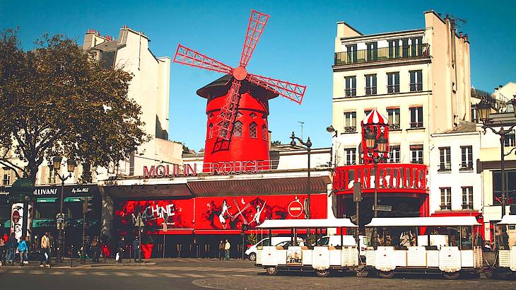 A bright red windmill protruding from the top of the Moulin Rouge building