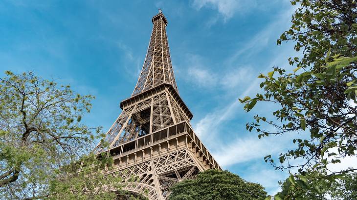 A tall pointy tower against a blue sky with greenery below