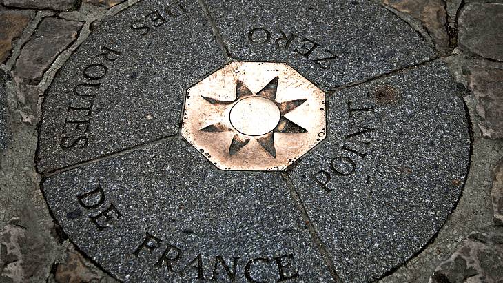 An up-close shot of a metallic, star shaped compass in the ground