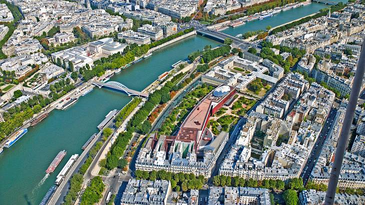 Aerial view of a city with tree-lined streets and a river with bridges in the center