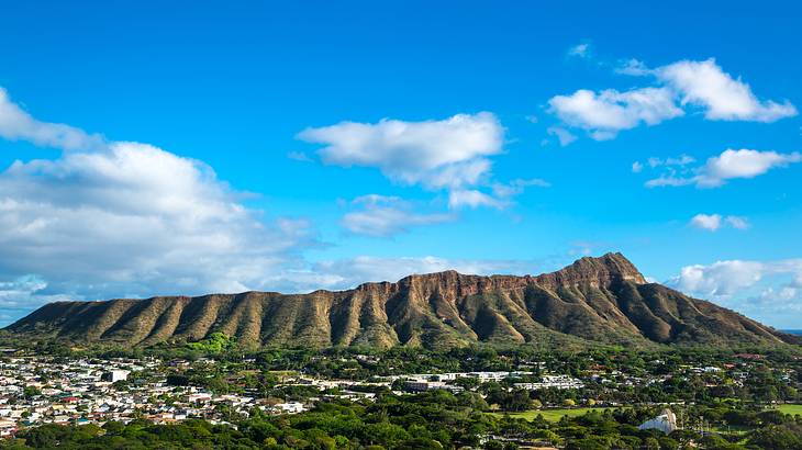 Aerial view of a volcano with buildings and tropical trees at its feet Aerial view of a volcano with buildings and tropical trees at its feet