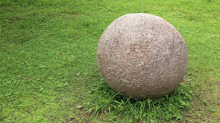 Mysterious stone sphere sitting on a green lawn