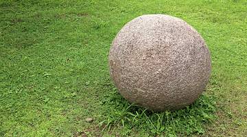 Mysterious stone sphere sitting on a green lawn