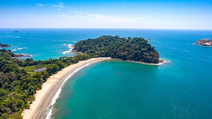 A white sand beach with lush vegetation trees surrounded by blue water