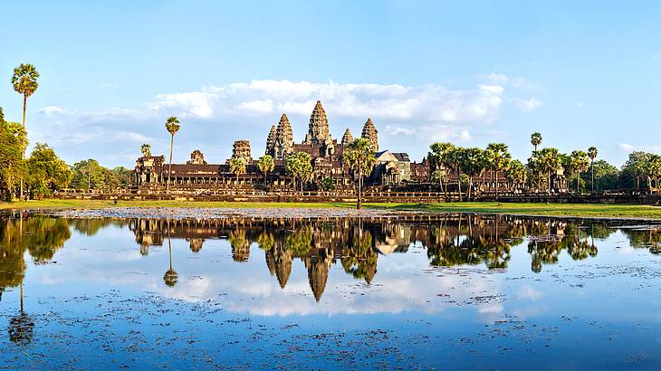 A magnificent, gigantic temple with 5 pointy tops and palm trees reflected in water