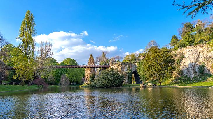 Panoramic view of Buttes-Chaumont Park with greenery and water in front on a nice day