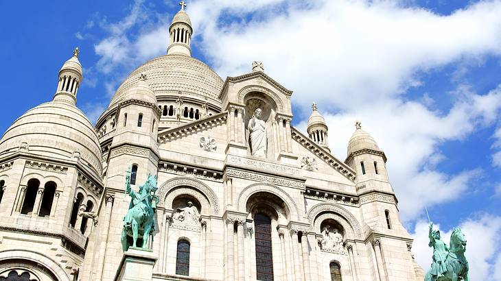 Close-up shot of Sacré-Cœur Basilica's facade from below on a partly cloudy day