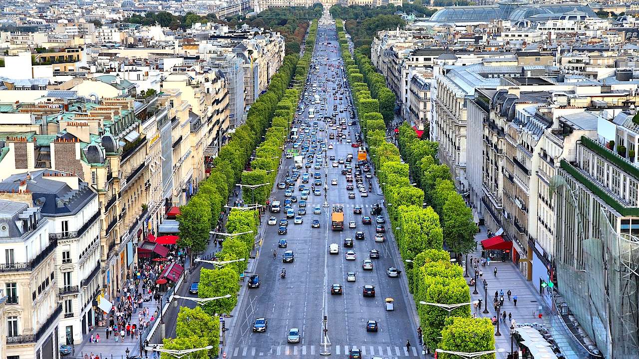 Aerial view of a popular French street lined by trees, buildings, and is full of cars