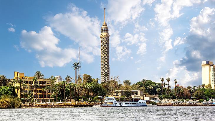 The Cairo Tower overlooking a body of water with boats surrounded by greenery
