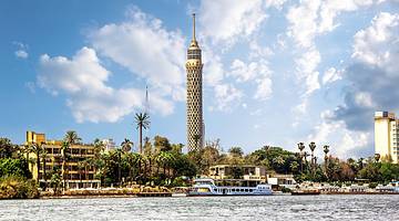 The Cairo Tower overlooking a body of water with boats surrounded by greenery